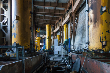 Interior of dam reservoir at hydroelectric power station with industrial equipment and machinery, yellow columns and structural elements.