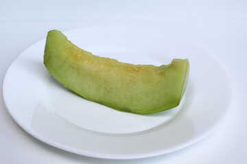 One cut green cantaloupe or melon, on white plate, isolated on white background