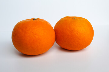 Two unpeeled orange fruits, isolated on white background