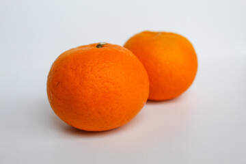 Two unpeeled orange fruits, isolated on white background