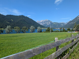 Achensee. Hinten die Alpen in Tirol. Vordergrund Holzzaun und Wiese