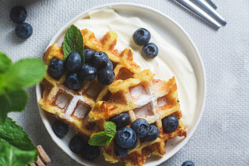 Belgian waffles with sour cream and blueberries in a plate