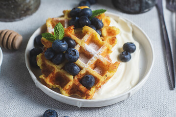 Belgian waffles with sour cream and blueberries in a plate