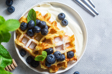 Belgian waffles with sour cream and blueberries in a plate