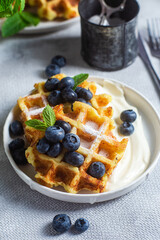 Belgian waffles with sour cream and blueberries in a plate