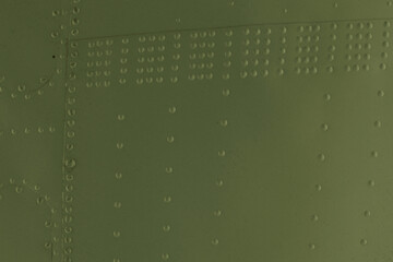 Metal wall with green rivets.