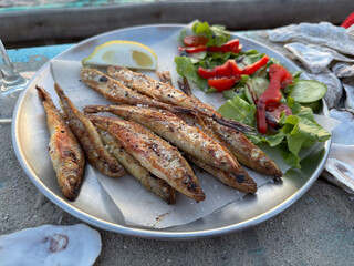 Plate of delicious grilled fish served with a fresh salad and a slice of lemon. Perfect for seafood lovers and healthy eating.