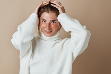 Stressed woman in white sweater holding head in hands, concept of stress and anxiety