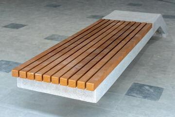 Modern bench with concrete base and wooden seat  on a public area 