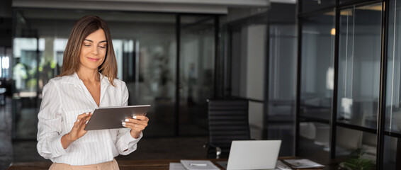 Latin mature adult professional business woman looking at online trade app. European businesswoman...