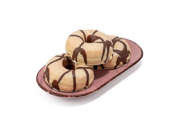Three donuts with chocolate drizzle on top of a pink plate. The plate is on a white background