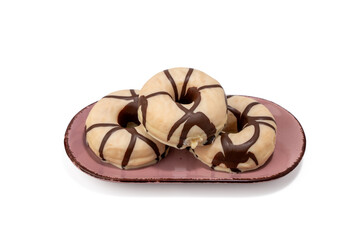 Three donuts with chocolate stripes on them are on a pink plate. The plate is on a white background