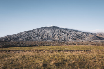 Wide shot of Snæfellsjökull on Iceland on a sunny day with a blue and cloudless sky.