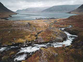 View from the path up to Dynjandi Waterfall on Iceland down to the parking area and with a full view on the fjord. The river is leading the view from the foreground down to the fjord.