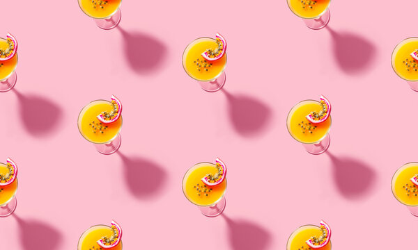 Seamless pattern of martini cocktails with sliced passion fruit bold shadow at the pink background. Cocktail pattern for concept design. Minimal style background. Top view