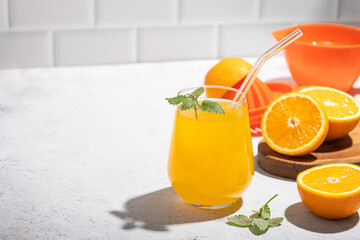 fresh orange juice in a glass with mint and a slice of fruit on the table against a white brick wall. Copy space
