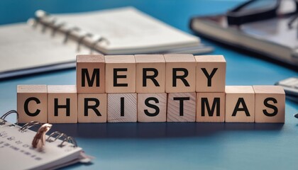 merry chrstmas word written on wooden blocks on blue office table with calendar. 