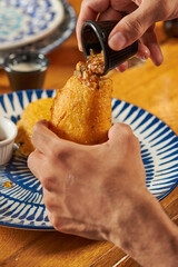 mano de hombre echando aji a una empanada colombiana   sobre una mesa de madera
