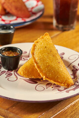 empanada colombiana  con aji en un plato sobre una mesa de madera