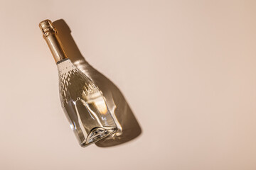 Yellow bottle of champagne on a beige background with caustic shadow. copy space
