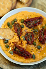 Hummus with sun-dried tomatoes and capers on a plate