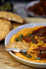 Hummus with sun-dried tomatoes and capers on a plate