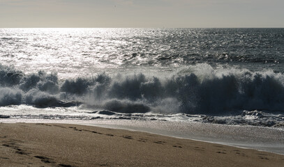Ocean shore before sunset, white waves on the shore, horizon visible