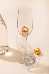 A bottle of champagne and two glasses with New Year's balls on a beige background. Celebrating Christmas and New Year. Copy space