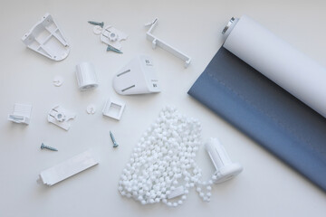 Roller blinds and spare parts on white windowsill. Preparation for the installation of roller blinds