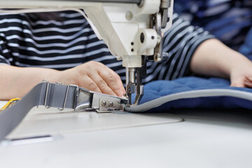 Close-up of hands in a sewing workshop, who sews a cape for a riding saddle.