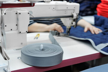 A close-up of a ribbon in a sewing workshop where a riding saddle cape is being sewn.