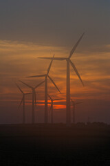 wind turbines at sunset with hazy sky