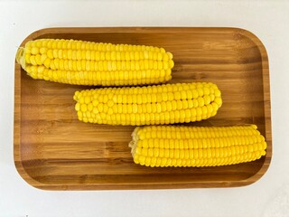 Sweet corn on a wooden plate. Bright and yellow food. Small grains on the rock