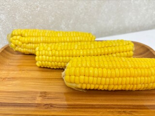 Sweet corn on a wooden plate. Bright and yellow food. Small grains on the rock