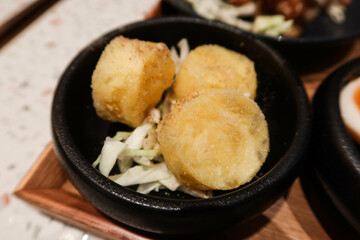 close up of Japanese style seasoned deep fried braised egg tofu in a black bowl