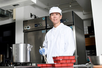 弁当箱に料理を詰める男性の調理スタッフ