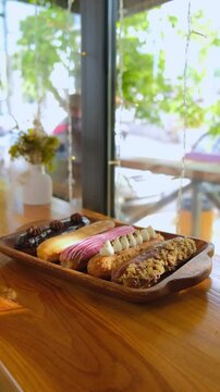 delicious eclairs are on the table. Variety of eclairs with glossy chocolate topping, lined up neatly on a rustic wooden table