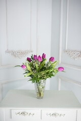 purple tulips in a crystal vase on a retro background