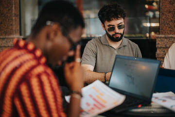 Business partners discussing a new project, analyzing statistics, and strategizing in a modern coffee shop setting, focusing on planning and teamwork.