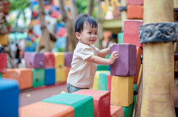 A young child is playing with blocks in a colorful play area. The child is smiling and he is enjoying the activity