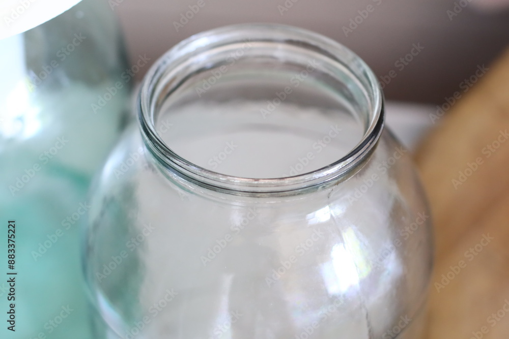 Poster a close-up view of a glass jar sitting on a table, filled with unknown contents.