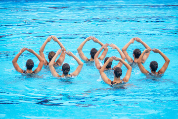 Synchronized swimmers team performing artistic swimming in the swimming pool
