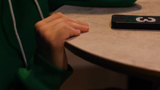 order readiness pager in a fast food restaurant on the table and a child's hand of a client waiting for the order to be prepared. fast food restaurant preparing the order