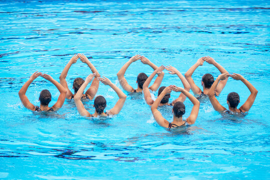 Synchronized swimmers team performing artistic swimming in the swimming pool