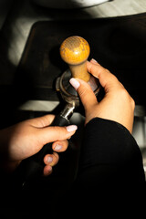 Close-up of a barista's hands preparing coffee using a hand press, ground coffee using tempering....