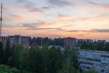Sunset gradient sky, clouds, buildings, residential houses. Late evening. Greenery, the beginning...