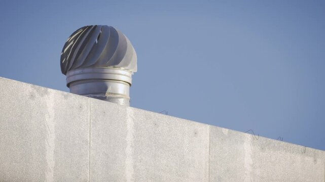 Ventilation outlet of a building in the shape of a spinning whirlpool. Blue sky. Turning on 