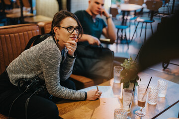 Casual business meeting in a modern coffee shop featuring people working and discussing ideas. Relaxed and professional atmosphere.