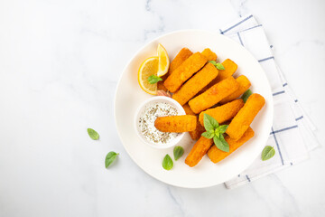 Fish and chips .Close up of crispy breaded deep fried fish fingers with breadcrumbs served with remoulade sauce and lemon