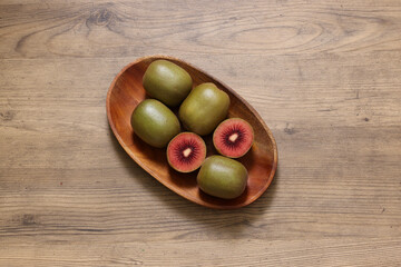 木製の皿に盛った実の赤いキウイフルーツ